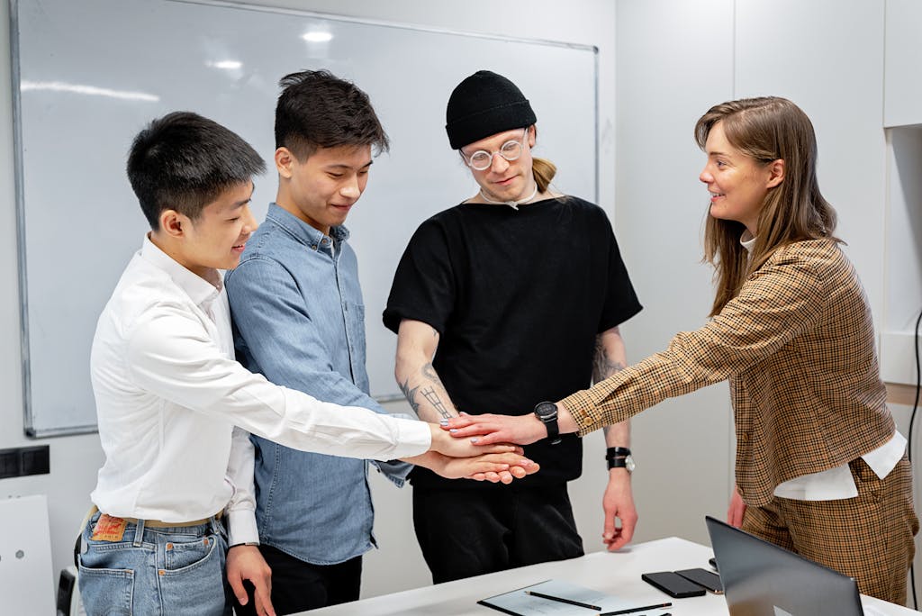 Group of diverse colleagues stacking hands in an office, symbolizing teamwork and collaboration.